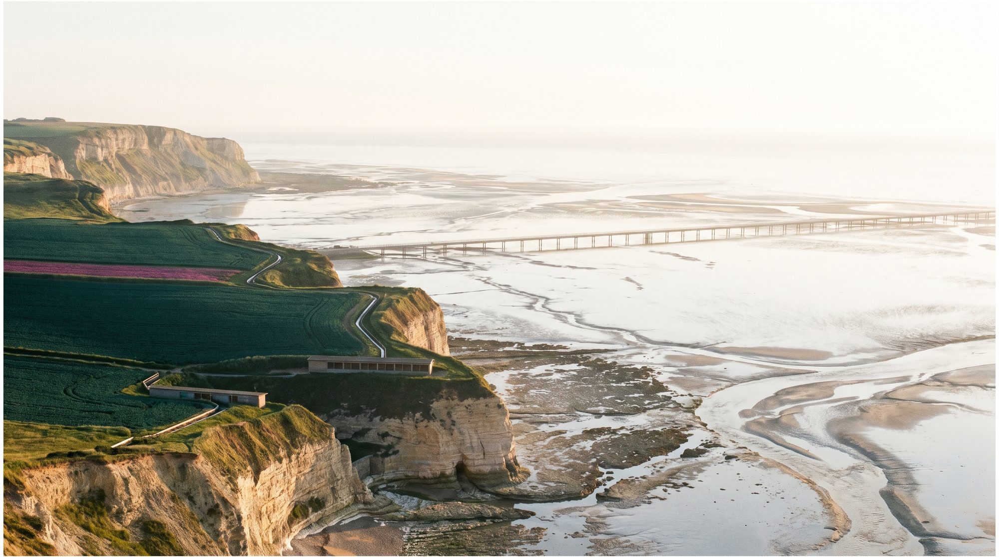 Tidal flats mirroring a pale sky, terraces on the headland beyond